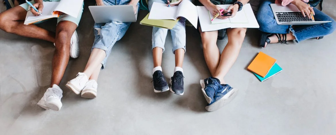 Overhead portrait of young people with laptops and smartphones, sitting together on the floor. Students writing lectures holding textbooks on their knees.. formacion
